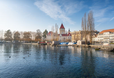 Buildings by river against sky