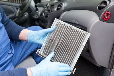 Midsection of man repairing air conditioner in car