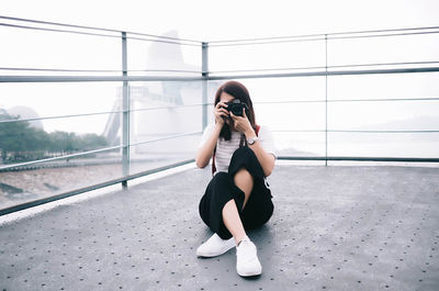 Full length of woman photographing on railing