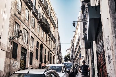 Vehicles on road by buildings in city against sky