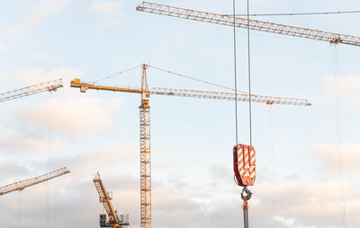 Low angle view of cranes against sky