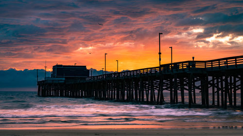 Pier on sea against sky during sunset