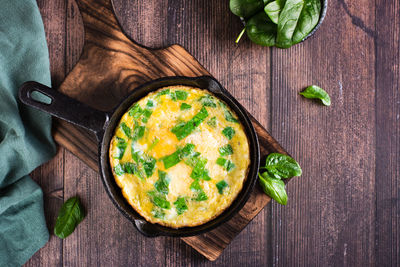 Omelet with spinach and cheese in a pan on the table. ketogenic diet. top view