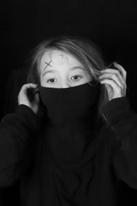 Portrait of girl covering face against black background