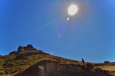 Low angle view of rock against sky on sunny day