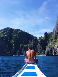 Rear view of shirtless man in sea against sky