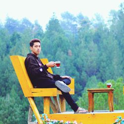 Portrait of man using mobile phone while sitting on field