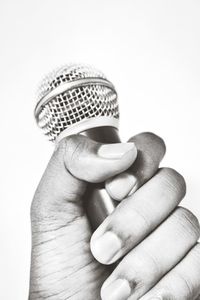 Close-up of hand holding guitar against white background