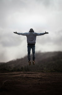 Full length of man jumping on field against sky