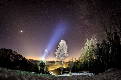 Rear view of man with flashlight standing against star field