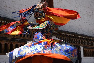 Low angle view of person wearing colorful costume while dancing against wall