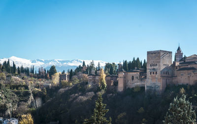 Historic building and trees against clear blue sky