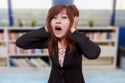 Portrait of woman screaming while standing in office