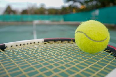 Close-up of tennis ball and racket at court