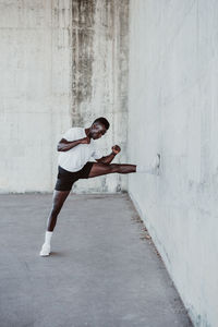 Male athlete exercising by white wall