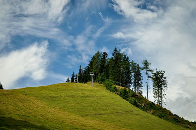 Trees on landscape against cloudy sky