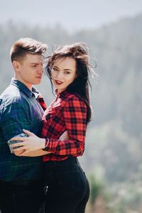 Loving young couple standing in forest