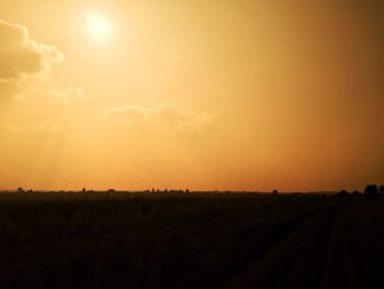 Scenic view of field against dramatic sky during sunset