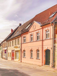 Street by buildings in town against sky