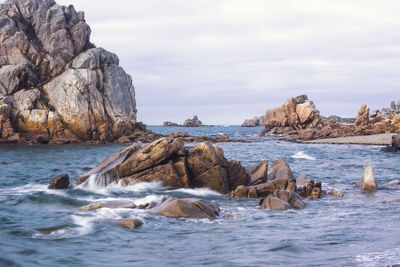 Rocks on sea shore against sky