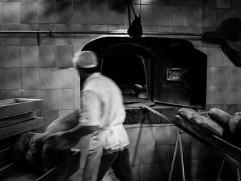 Rear view of man baking bread at bakery