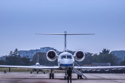 Man standing in front of airplane against clear sky