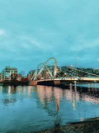 Bridge over river by buildings against sky