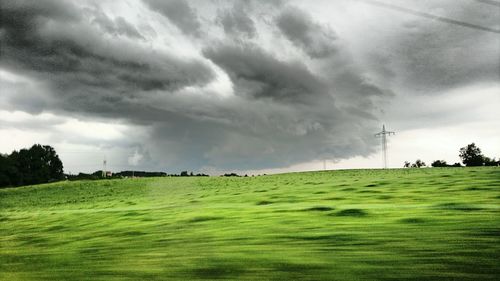 Scenic view of grassy field against cloudy sky