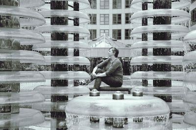Side view of mature woman sitting by fountain on bench