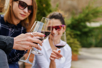 Close-up of woman holding woman wineglass sitting outdoors