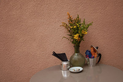 Flower vase on table against wall