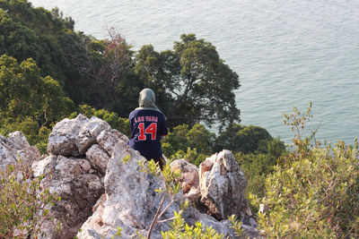 Rear view of man standing on cliff against sky