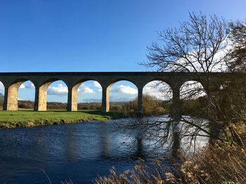 Arch bridge over river against sky