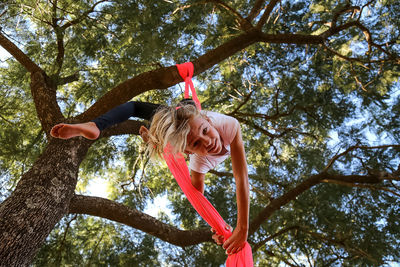 Low angle view of girl hanging on tree