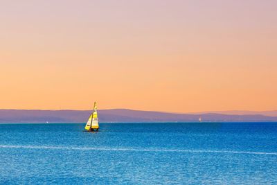 Sailboat in sea against sky during sunset