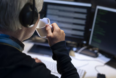 Male programmer working on computer and drinking from mug
