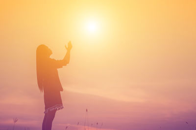 Silhouette person standing against orange sky