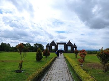 Panoramic view of footpath amidst field against sky