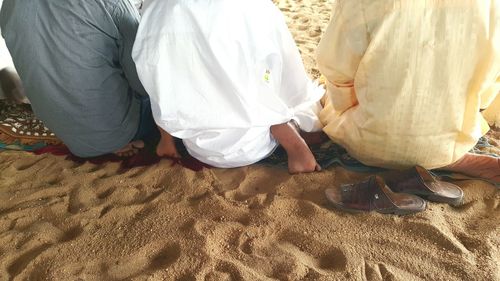 Rear view of three men sitting on ground