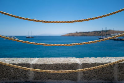 Close-up of rope against sea against clear blue sky