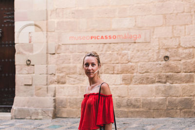 Portrait of a smiling young woman standing against brick wall