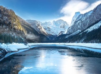 Frozen lake by snowcapped mountains against sky