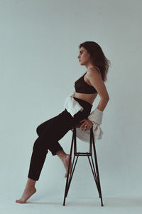 Woman looking away while sitting against white background