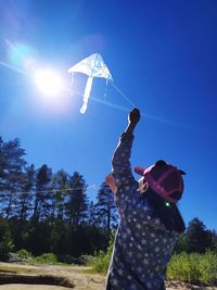 Low angle view of person holding umbrella against blue sky