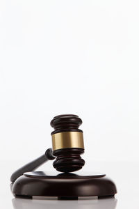 Close-up of gavel on wood against white background