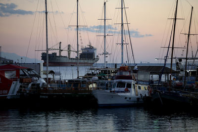 Sailboats moored at harbor against sky during sunset