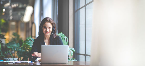 Young woman using mobile phone while sitting in office