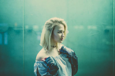 Portrait of young woman against wall