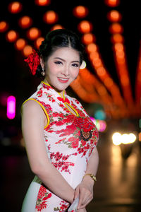 Portrait of young woman wearing cheongsam during festival at night