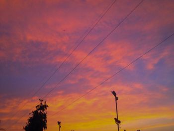 Low angle view of electricity pylon against dramatic sky